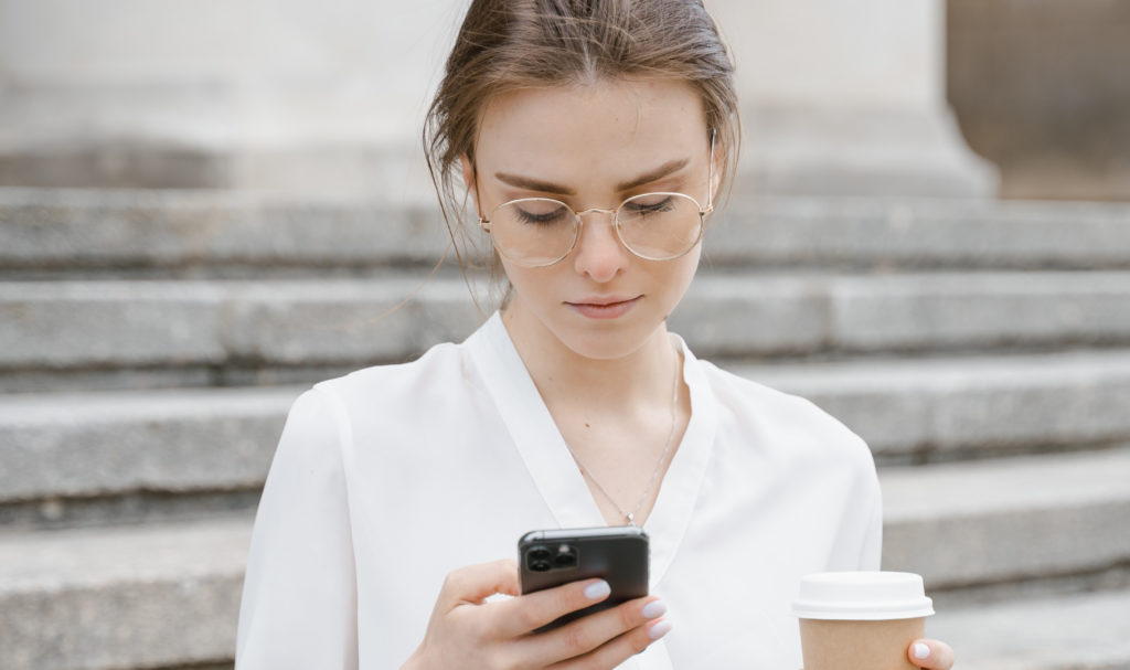 Frau mit Brille und Handy in der Hand