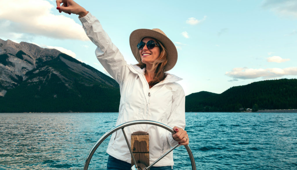 Frau mit Sonnenbrille auf einem Boot am Steuer